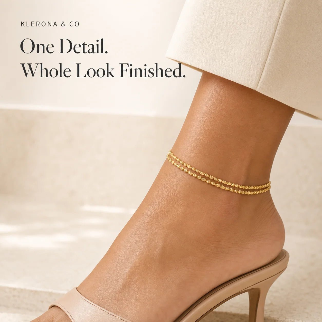 Gold double-strand anklet styled with a neutral heel