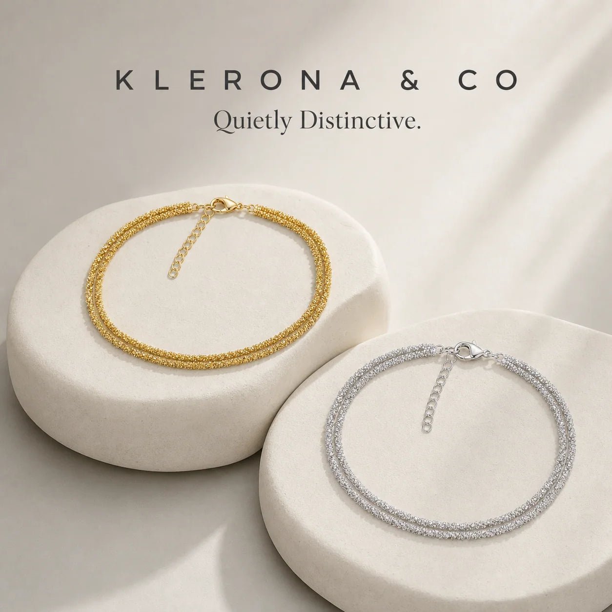 Gold and silver double-strand anklets arranged on warm stone forms